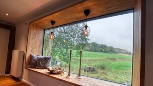 Une pièce dotée d’une grande fenêtre, de poutres en bois et offrant une vue sur un paysage verdoyant.