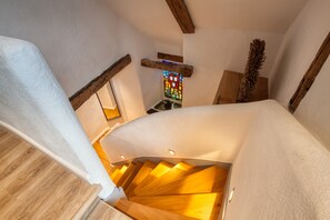 Un escalier en colimaçon avec des marches en bois et un mur blanc.