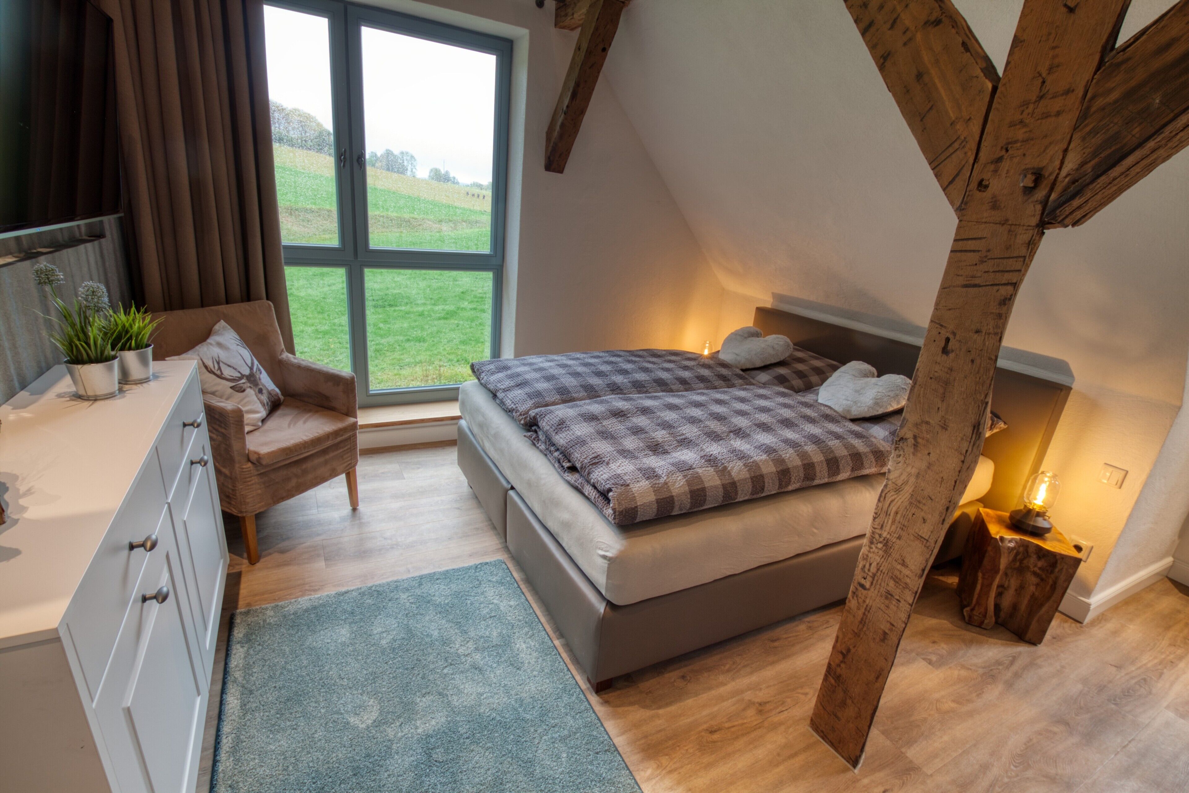 Een slaapkamer met een bed, een stoel, een bureau, een raam en een lamp.
