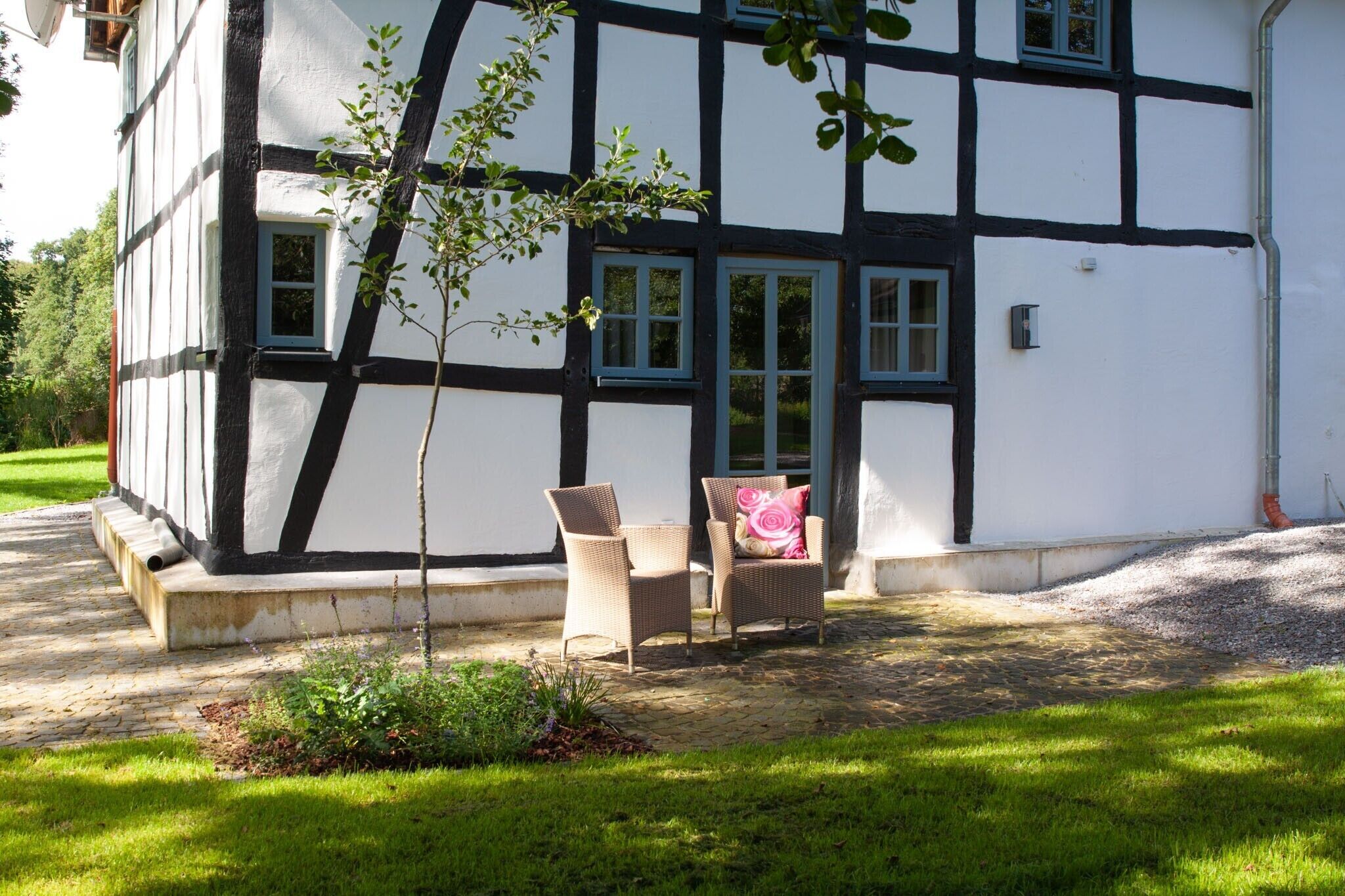 Il s’agit d’un bâtiment traditionnel à colombages, doté d’un petit jardin où l’on trouve deux fauteuils en osier et un coussin rose.