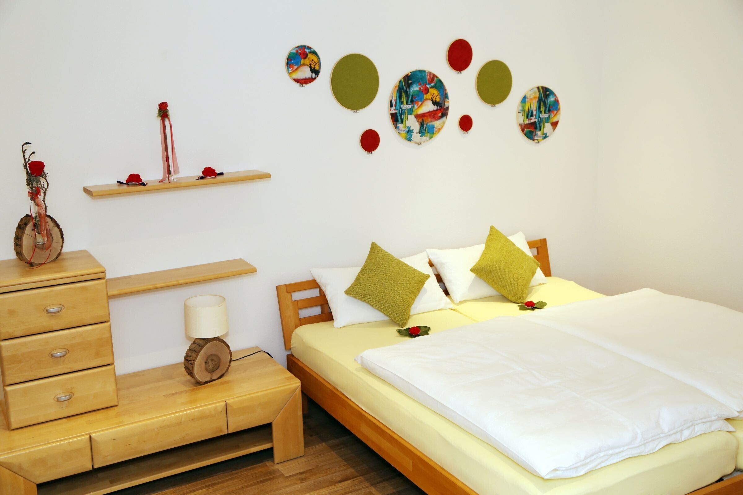 Une chambre à coucher bien rangée, avec un lit, des tables de chevet, une commode, une lampe et des décorations murales.