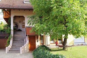 A house with a staircase leading to a door, a tree in the front yard, and a bench. - Studio Apartment "Schwarzwaldstüble" with Shared Terrace, Shared Garden & Wi-Fi (Oberharmersbach)