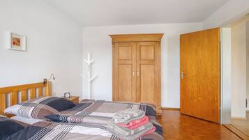 A bedroom with a wooden bed, a wooden wardrobe, a bedside table with a lamp, and a framed picture on the wall.