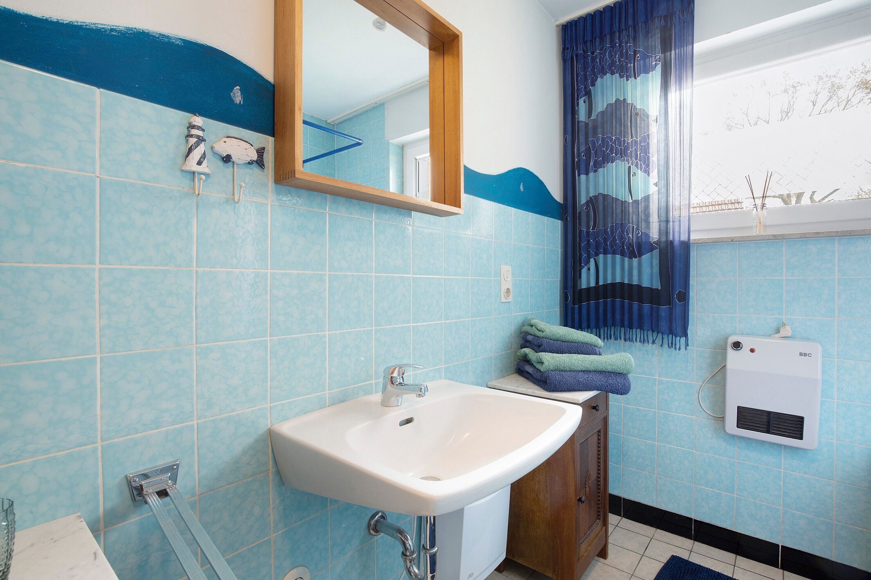 A bathroom with a sink, mirror, towel rack, and a heater.