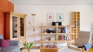 A living room with a sofa, armchair, bookshelf, and a cabinet.