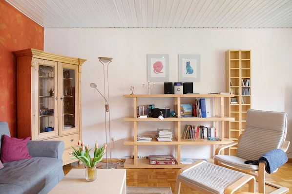 A living room with a sofa, armchair, bookshelf, and a cabinet.