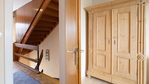 A wooden staircase with a handrail, a wooden door with a handle, and a patterned rug on the floor.