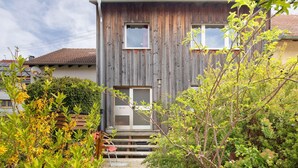 A two-story wooden house with a small front porch and a satellite dish.