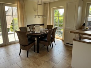 A dining area with a table, chairs, a menu, and a window with a view of greenery. - Holiday Home 'Villa Sorgenfrei' with Lake View, Private Terrace and Wi-Fi (Zinnowitz)