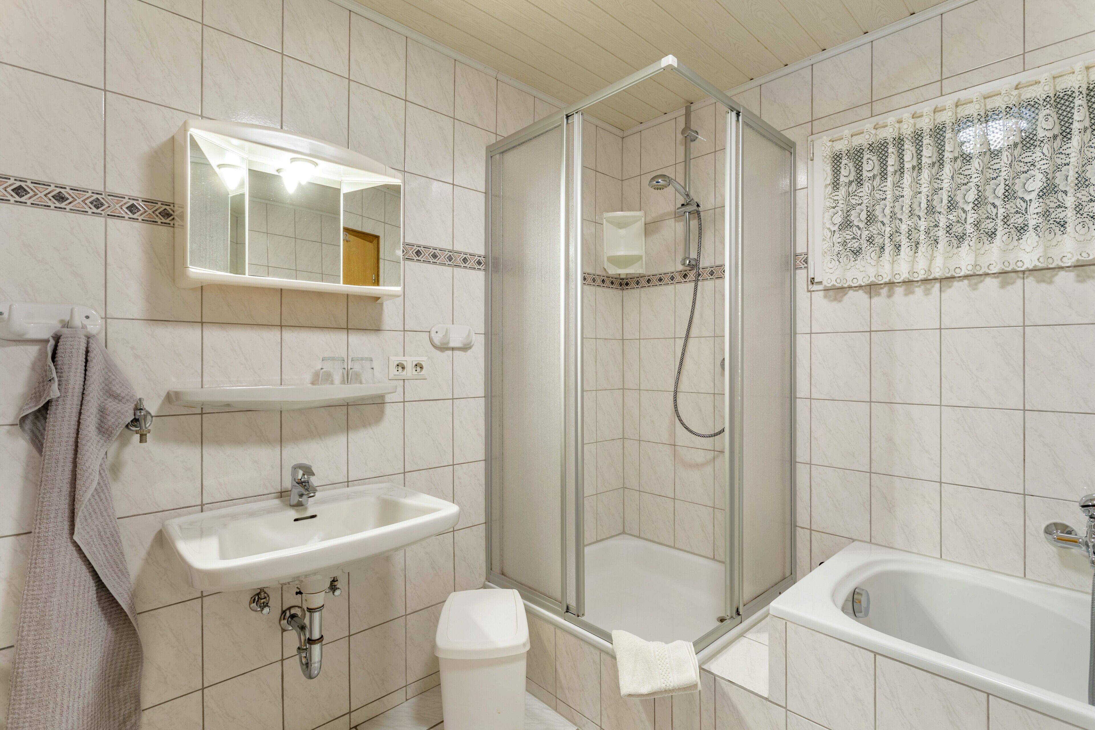 A bathroom with a shower, sink, toilet, and a mirror.