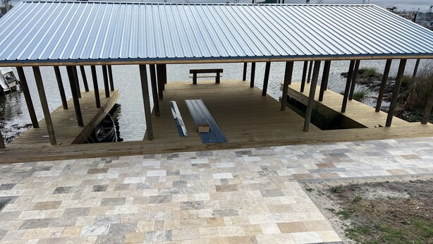 A covered wooden deck with a metal roof, a bench, and a small square opening.