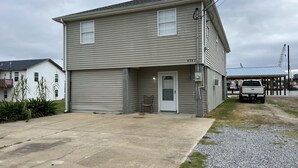 A two-story building with a garage door, a covered porch, and a visible address number.