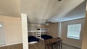 A room with bunk beds, a wooden table, and chairs.