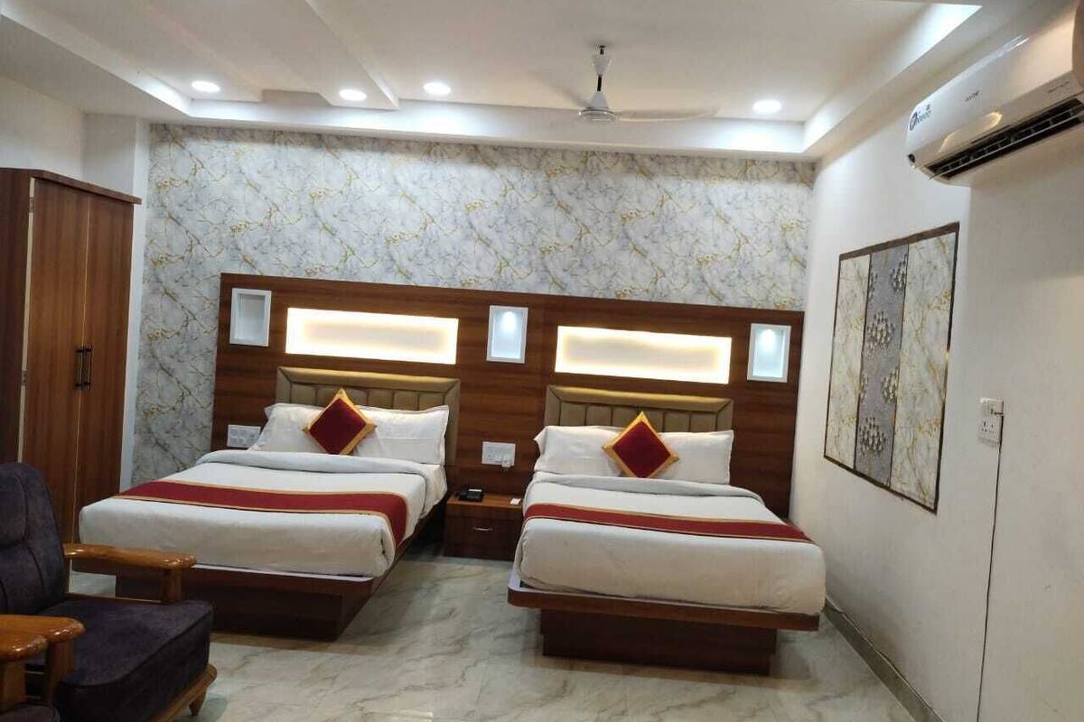 Ein Hotelzimmer mit zwei Betten, Holz-Kopfteilen, Wänden mit Marmoroptik und einem Deckenventilator.