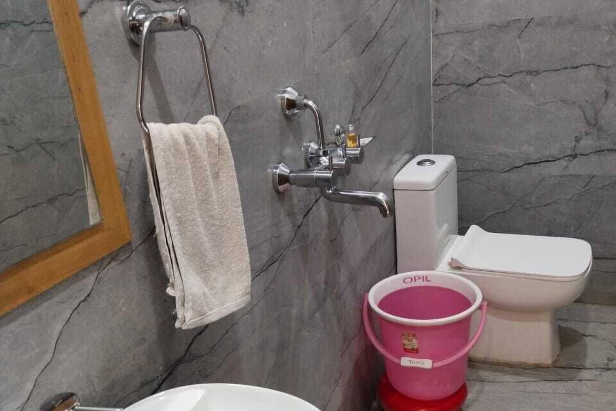 Ein Badezimmer mit einem weißen Waschbecken, einer Toilette und einem rosa Eimer.
