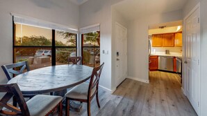 A dining area with a round table and chairs, a kitchen with wooden cabinets, and a sliding glass door leading to an outdoor patio.