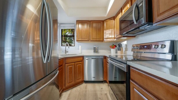 A modern kitchen with stainless steel appliances, wooden cabinets, and a dishwasher.