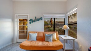 A modern living room with a sofa, a small table, and a window with a view of a mountain landscape.
