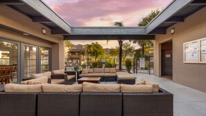 A covered outdoor seating area with wicker furniture and a glass enclosure.