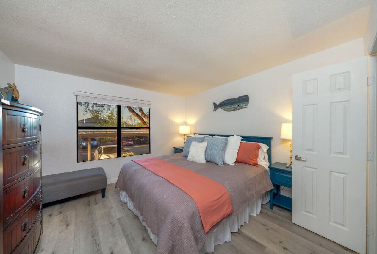 Une chambre à coucher comprenant un lit, une commode, un banc, une fenêtre donnant sur un paysage agréable et une porte.