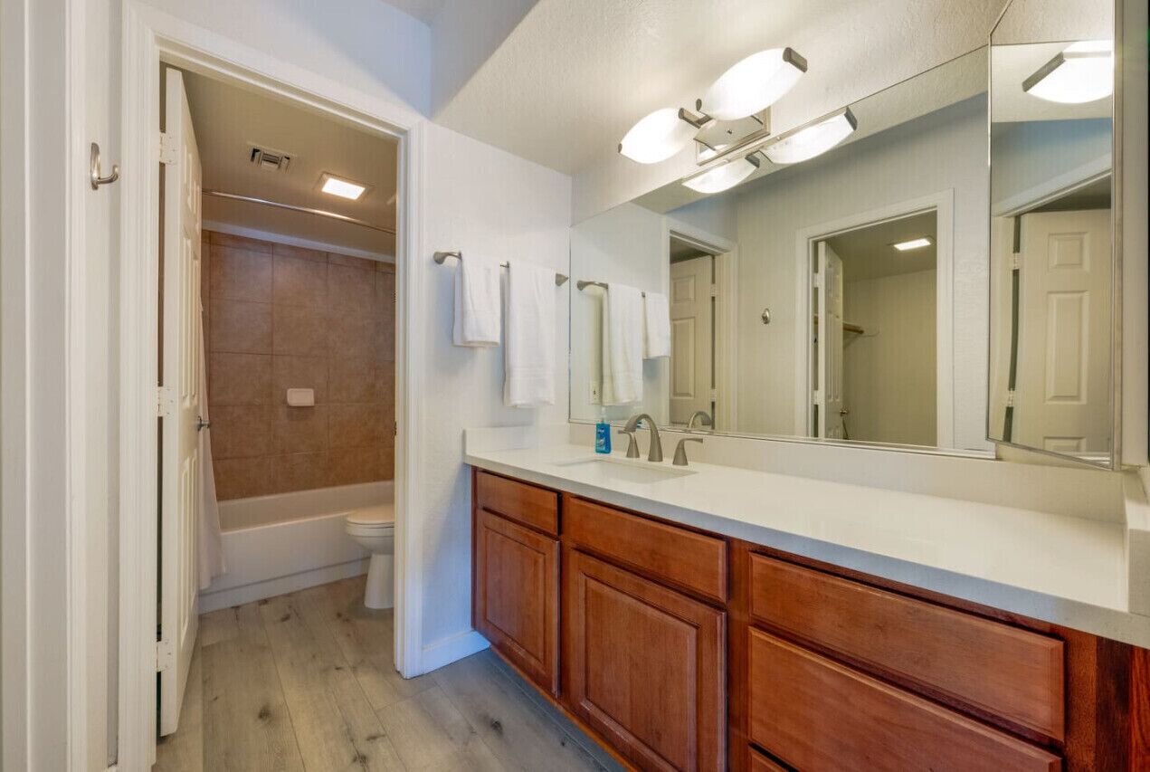 Une salle de bain avec un meuble-lavabo en bois, un grand miroir et un espace douche.