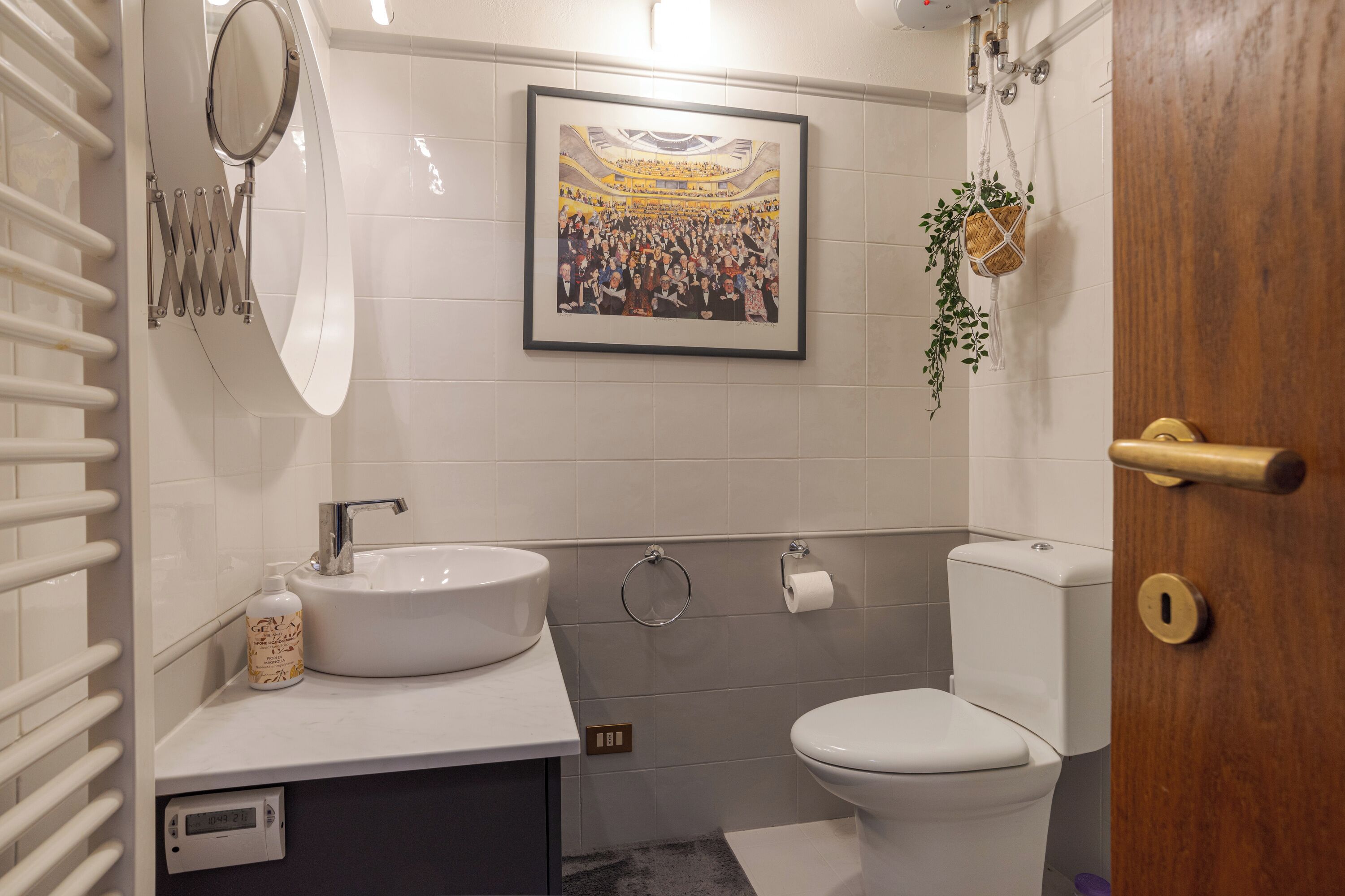 Une salle de bain avec un lavabo blanc, des toilettes et un tableau encadré au mur.