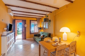 Un salon confortable avec un canapé, une table à manger et des chaises, un téléviseur et une lampe.