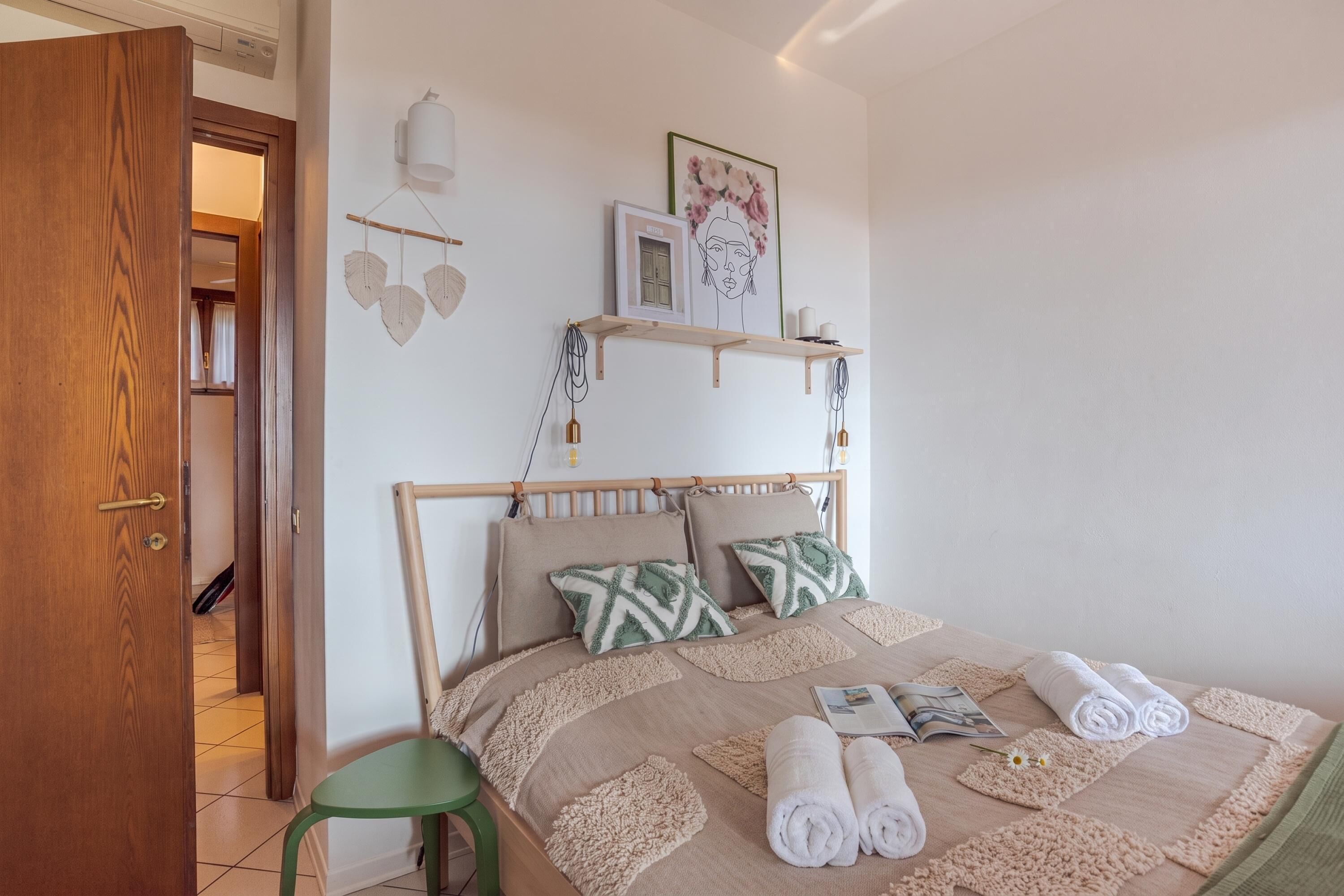 A bedroom with a bed, a green chair, and a wooden door.