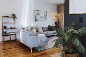 A living room with a sofa, a bookshelf, a framed picture, and a potted plant.