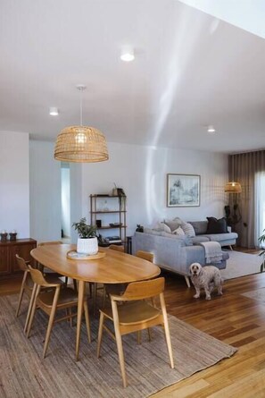 A spacious living area with a wooden dining table, a sofa, and a dog.