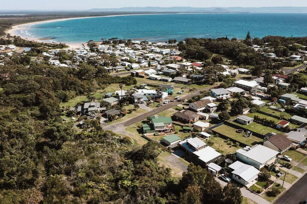 An aerial view of a coastal residential area with houses, roads, and a beach.