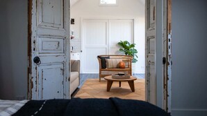 Een kamer met een landelijke deur, een bank, een ronde houten tafel en een bloempot met plant.