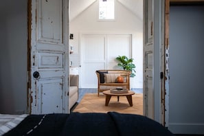Una habitación con una puerta rústica, un sofá, una mesa redonda de madera y una planta en maceta.