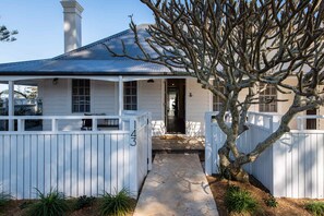 A white house with a covered porch, a stone pathway, and a fenced yard. - Soul of Gerringong Farmhouse (Gerringong)