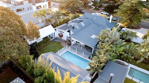 A residential property with a swimming pool, solar panels, and a covered patio area.