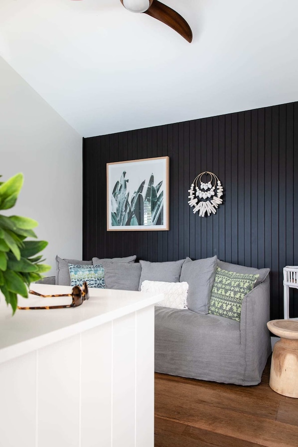 Una sala de estar moderna con un sofá gris, una impresión botánica enmarcada y un adorno de pared decorativo.