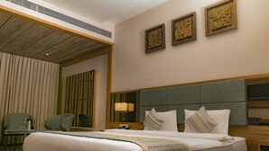 Habitación de hotel con una cama grande, un escritorio, una silla y un televisor montado en la pared.