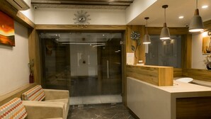 Un moderno vestíbulo de hotel con una recepción, asientos acolchados y un espejo grande.