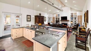 Una cocina amplia con una isla grande, un comedor con chimenea y una sala de estar con televisor y asientos.