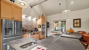 Una cocina moderna con electrodomésticos de acero inoxidable, armarios de madera y una isla grande con un lavamanos.