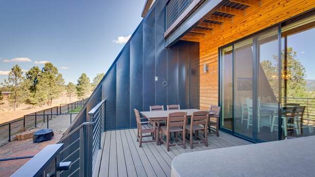 A modern outdoor deck with a dining table and chairs, a wooden railing, and a view of the surrounding landscape. - Angel Fire Home w/ Hot Tub < 1 Mi to Ski Slopes! (Angel Fire)
