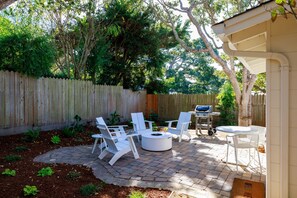 A patio with outdoor furniture, a barbecue grill, and a wooden fence.