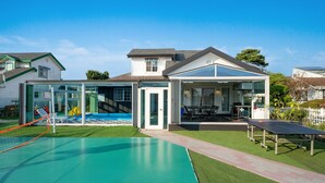Ein Wohnhaus mit Pool, überdachter Terrasse und Tischtennisplatte.