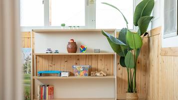 Una estantería de madera con juguetes, libros y una planta.