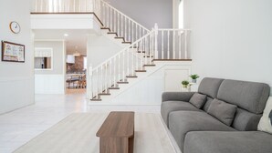 Ein modernes Wohnzimmer mit einem grauen Sofa, einem Holztisch und einer Treppe mit weißen Geländern.