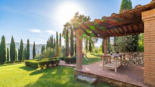 A patio with a pergola, stone walls, and a view of a lake. - Casale Al Sole Tra Le Vecchie Vigne, Radda in Chianti (Radda in Chianti)