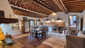 A spacious living area with a wooden ceiling, a dining table, and a sofa. - Casale Al Sole Tra Le Vecchie Vigne, Radda in Chianti (Radda in Chianti)