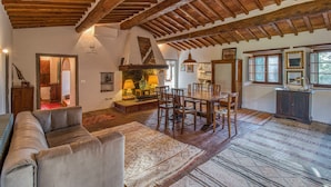 A spacious living room with a high wooden ceiling, a dining area with a wooden table and chairs, and a cozy seating area with a sofa and patterned rugs. - Casale Al Sole Tra Le Vecchie Vigne, Radda in Chianti (Radda in Chianti)