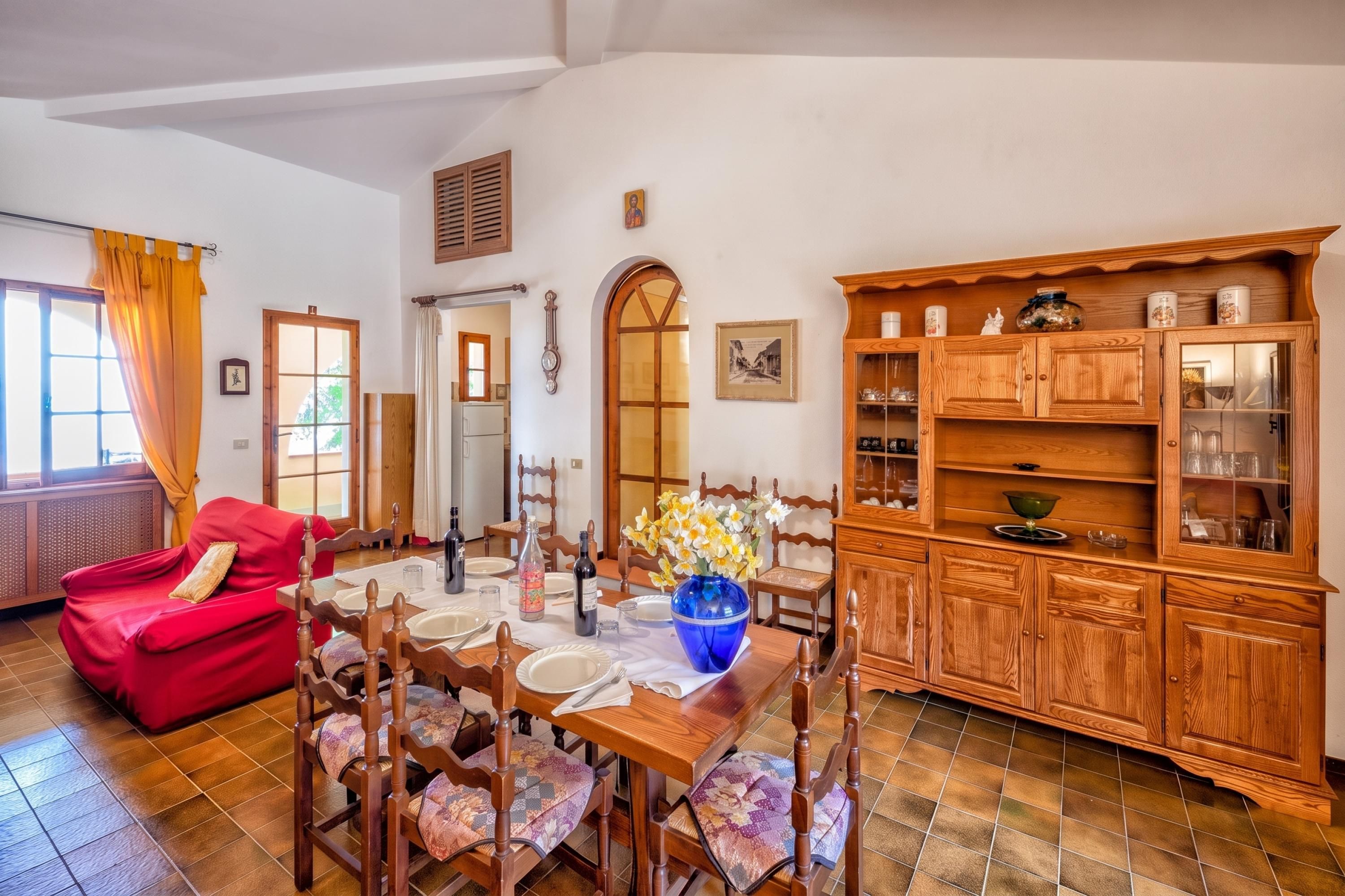 Un coin repas avec une table en bois dressée pour quatre personnes, entourée de chaises dotées de coussins à motifs.