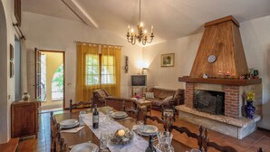 Ein Essbereich mit Holztisch, gedecktem Esstisch, Kamin und Fernseher im Hintergrund.